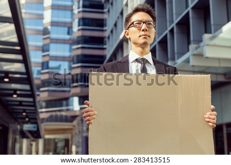 Businessman in a city street holding a blank banner