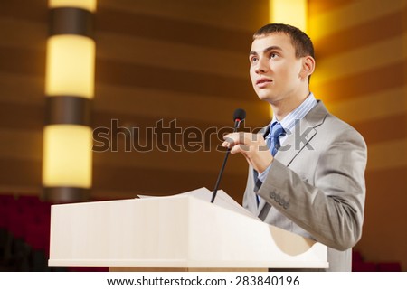 Businessman standing on stage and reporting for audience