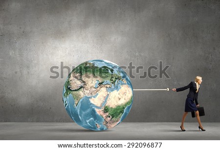 Young businesswoman with suitcase pulling Earth planet with lead. Elements of this image are furnished by NASA