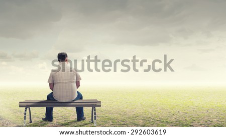 Fat man sitting on bench with his back and looking away