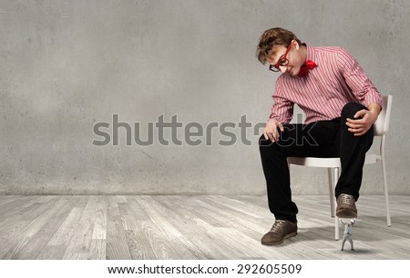 Guy sitting on chair and stepping on small business person
