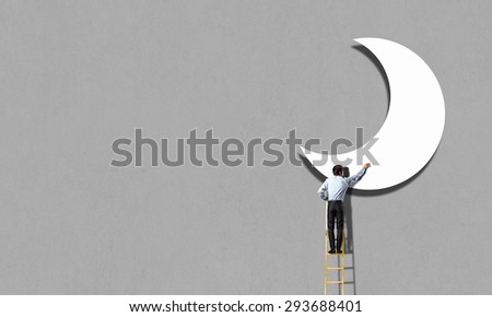 Rear view of man standing on ladder and reaching moon