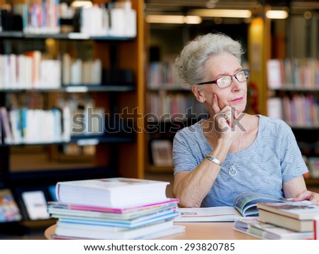 Elderly lady reading books in library