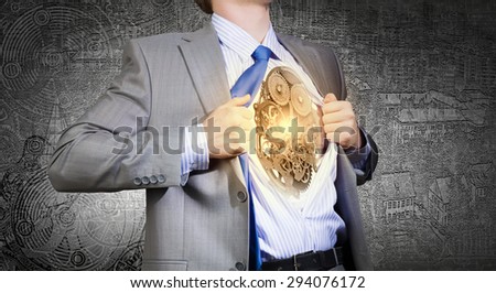 Young businessman in suit opening his chest and acting like super hero