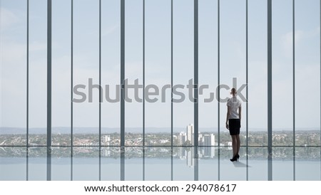 Businesswoman standing with back and looking in office window