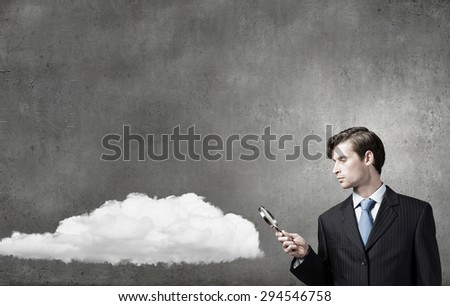 Businessman in suit looking through magnifying glass