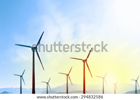 Concept of alternative electricity power with windmills on sunset background