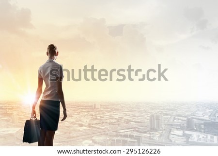 Rear view of businesswoman look at sunrise above city