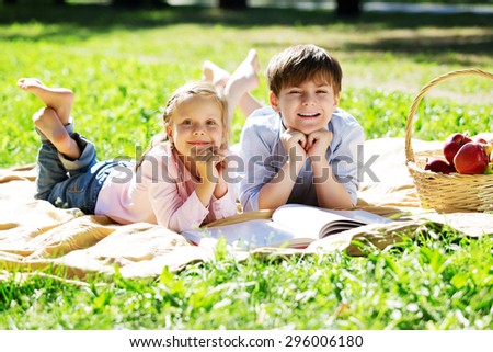 Sister and brother in the park reading a book