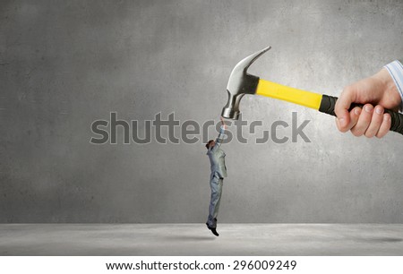 Close up of hammer in male hand attacking scared businessman