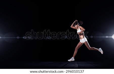 Running woman in sport wear on black background