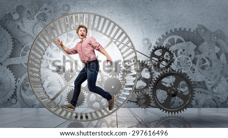 Young businessman running in wheel of gears mechanism