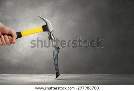 Close up of hammer in male hand attacking scared businessman