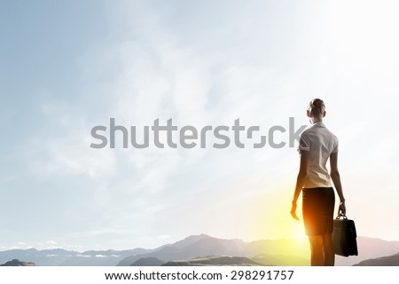 Rear view of businesswoman look at sunrise above mountain