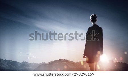 Back view of businesswoman against mountain landscape looking far away