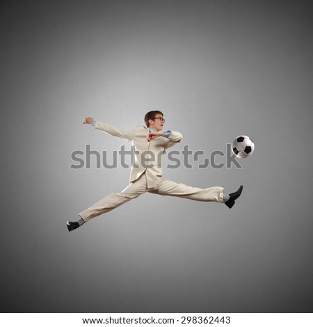 Businessman in suit hitting soccer ball in jump