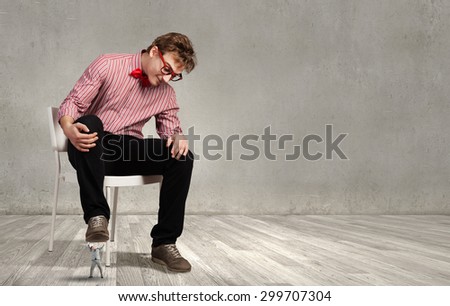 Guy sitting on chair and stepping on small business person