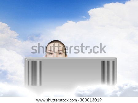 Young woman looking out above laptop monitor