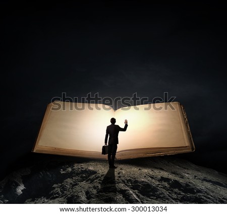 Big old opened book and miniature of businessman