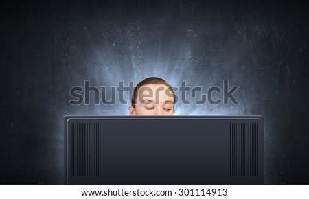 Young woman looking out above laptop monitor