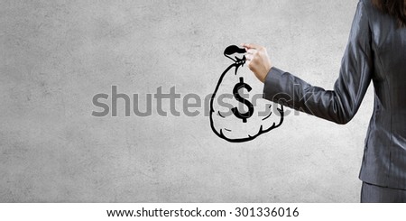 Back view of businesswoman drawing money bag on wall