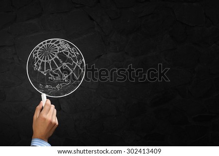 Close up of hand drawing globe on blackboard