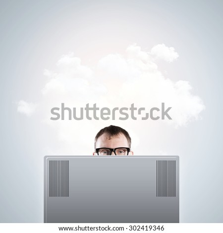 Young man looking out above laptop monitor