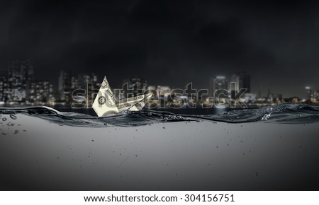 Ship made of dollar banknote sinking in water
