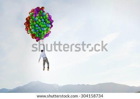 Young successful businessman flies on bunch of colorful balloons