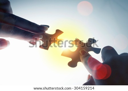 Hand connecting two jigsaw glowing puzzle pieces
