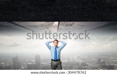 Young confident businessman with hands on head under pressure