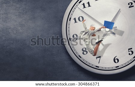 Concept of time with jumping businesswoman over big alarm clock