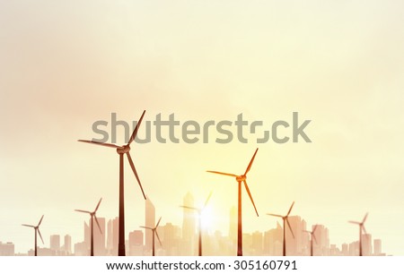 Concept of alternative electricity power with windmills on sunset background