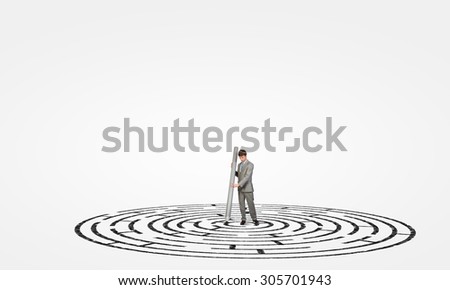 Young businessman drawing maze on floor with huge pencil