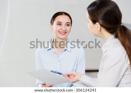 Two young women sitting at office having conversation