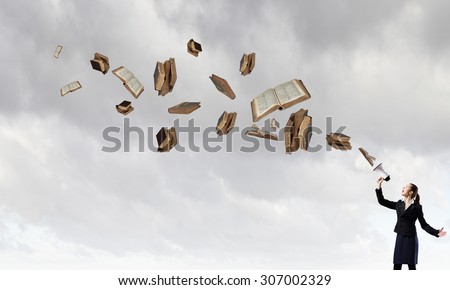 Young businesswoman screaming in megaphone and books flying out