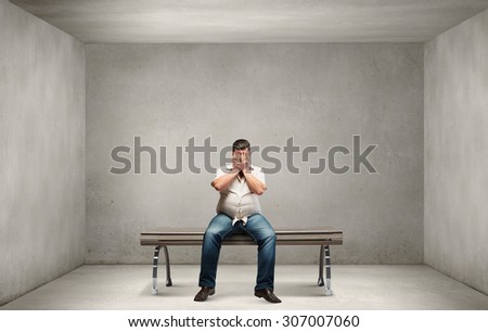 Fat man sitting on bench closing eyes with hands