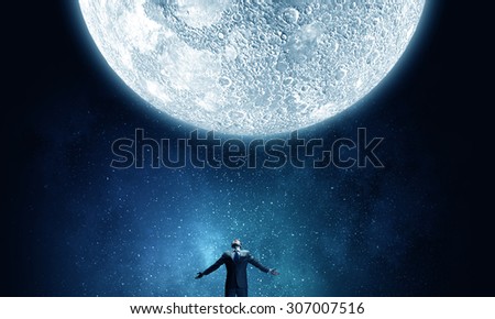Businessman with hands spread apart looking at moon above