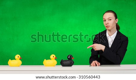 Young businesswoman pointing with finger at yellow rubber duck toy on table