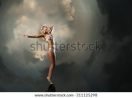 Hot young dancing woman in white bikini on dark background