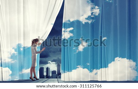 Businesswoman pulling curtain and cityscape behind it