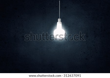 Glowing light bulb on dark background hanging from above
