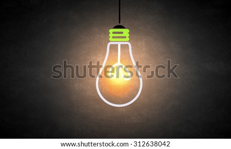 Glowing light bulb on dark background hanging from above