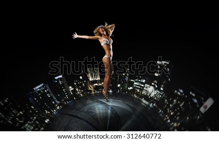 Hot young dancing woman in white bikini on night city background