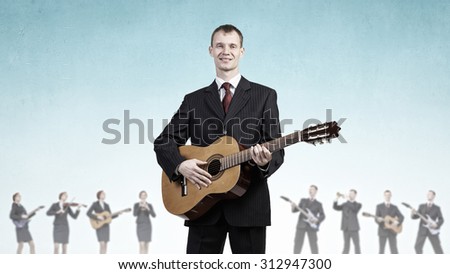 Young man in black suit playing acoustic guitar