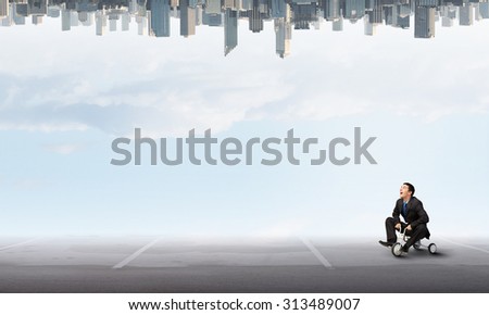 Young funny businessman riding three wheeled bicycle