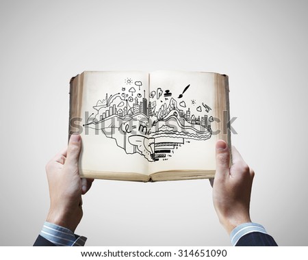 Close up of male hands holding opened book with sketches