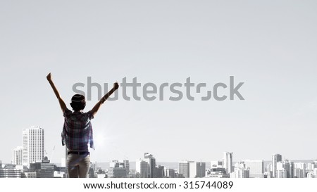 Back view of cheerful woman with hands up facing sunrise