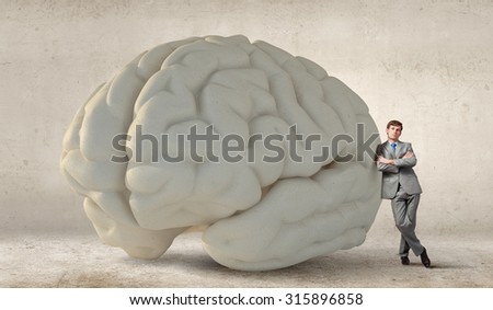 Young businessman leaning on big brain model