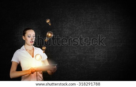 Young businesswoman using tablet pc and light bulbs flying out
